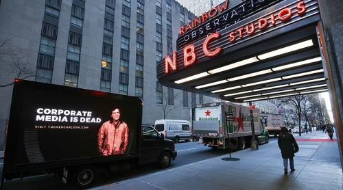Tucker Carlson instalează panouri publicitare "Mass-media corporatistă a murit"  în fața sediilor NYTimes, CNN, MSNBC și Washington Post 